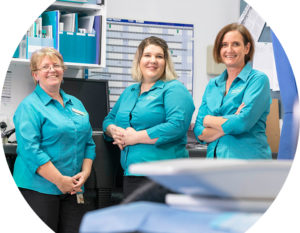 Image of three general practice staff, wearing aqua coloured business shirts smiling at the camera