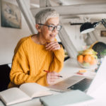 Older woman working on laptop Smiling senior woman with computer at home