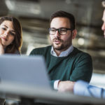 Young couple and real estate agent using laptop on a meeting in the office. Young couple using computer with their insurance agent on a meeting in the office.