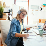 Mature woman working from home on laptop. Woman has blueprints on the table, dealing with investments and finances