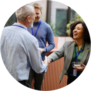 Female AGPAL Surveyor smiling and shaking hands with male AGPAL Surveyor while networking at an accreditation assessment